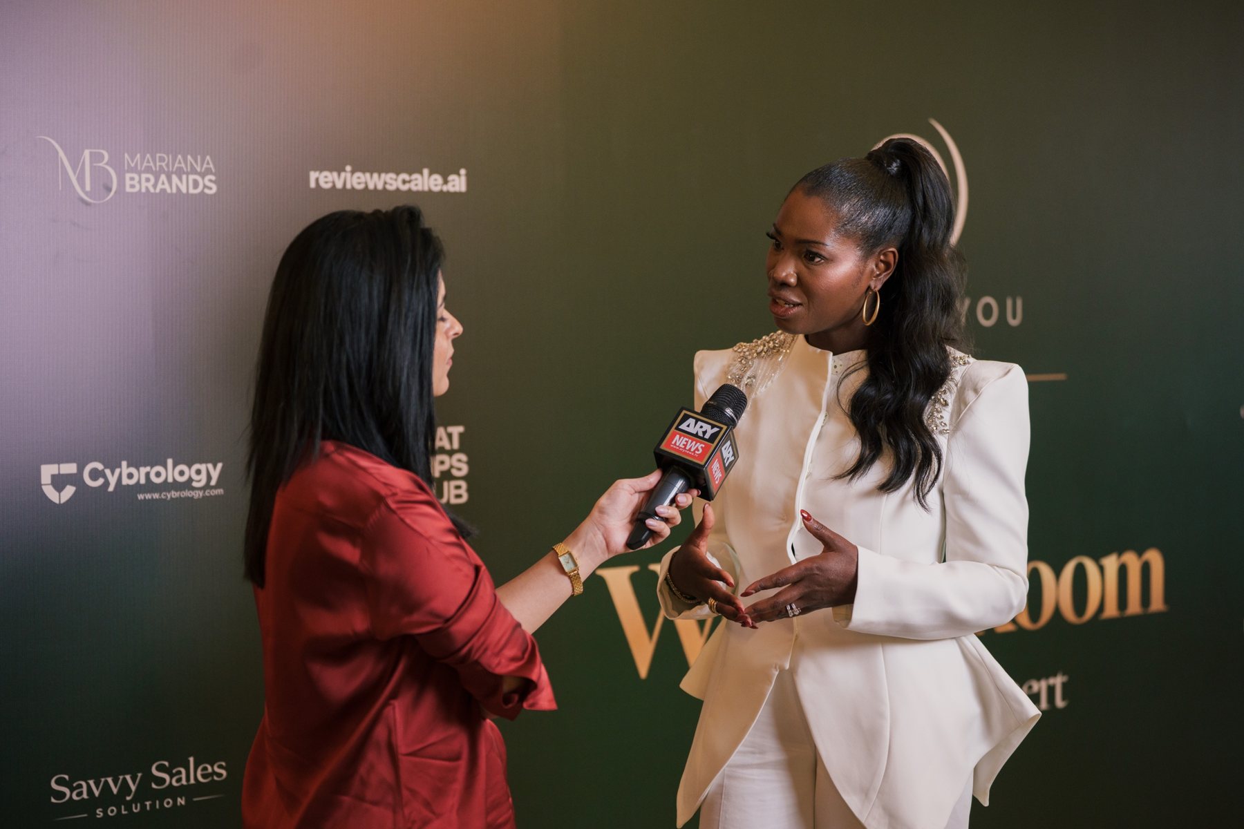 Ellen Mannaert speaking with a journalist in front of a press wall in Dubai